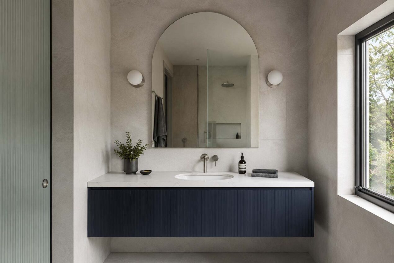 Arched frameless bathroom mirror above a single vanity in a contemporary Australian ensuite