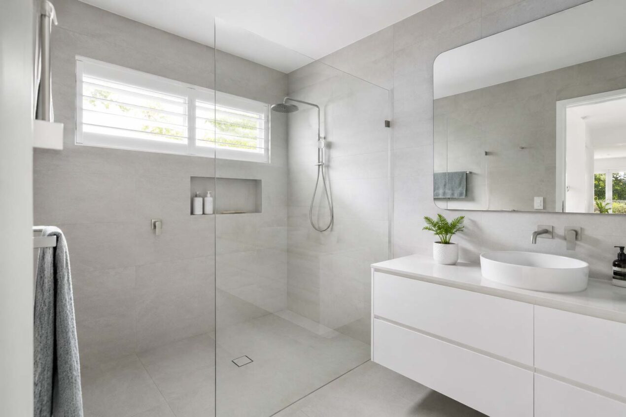 Low-visual-noise shower screen in a minimalist Australian bathroom with clear frameless glass