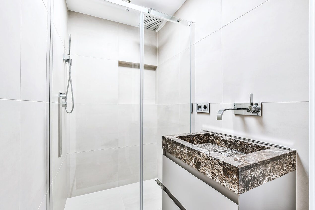 Minimalist bathroom with a sliding wall to wall shower screen and marble vanity