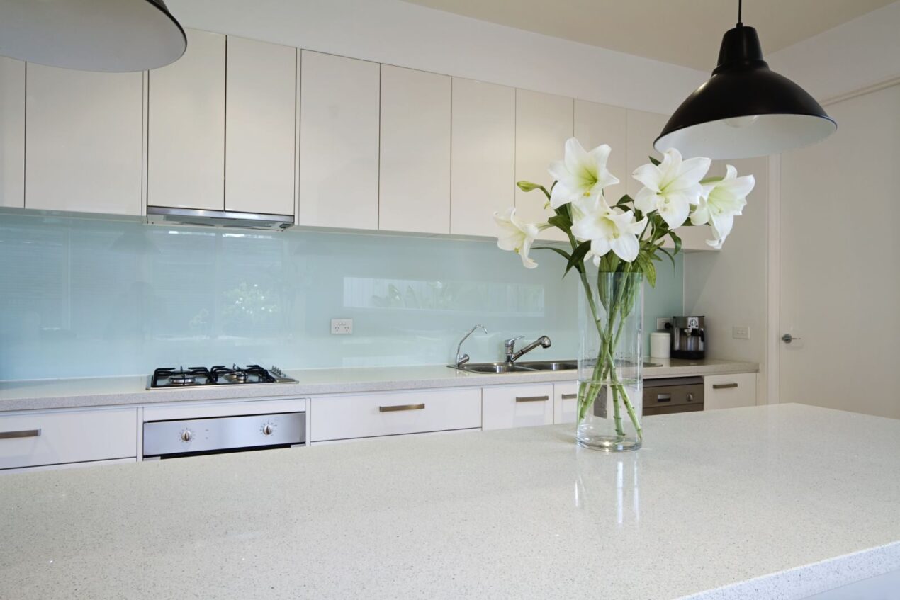 Modern kitchen with a white frosted glass splashback, navy blue cabinets and marble countertop
