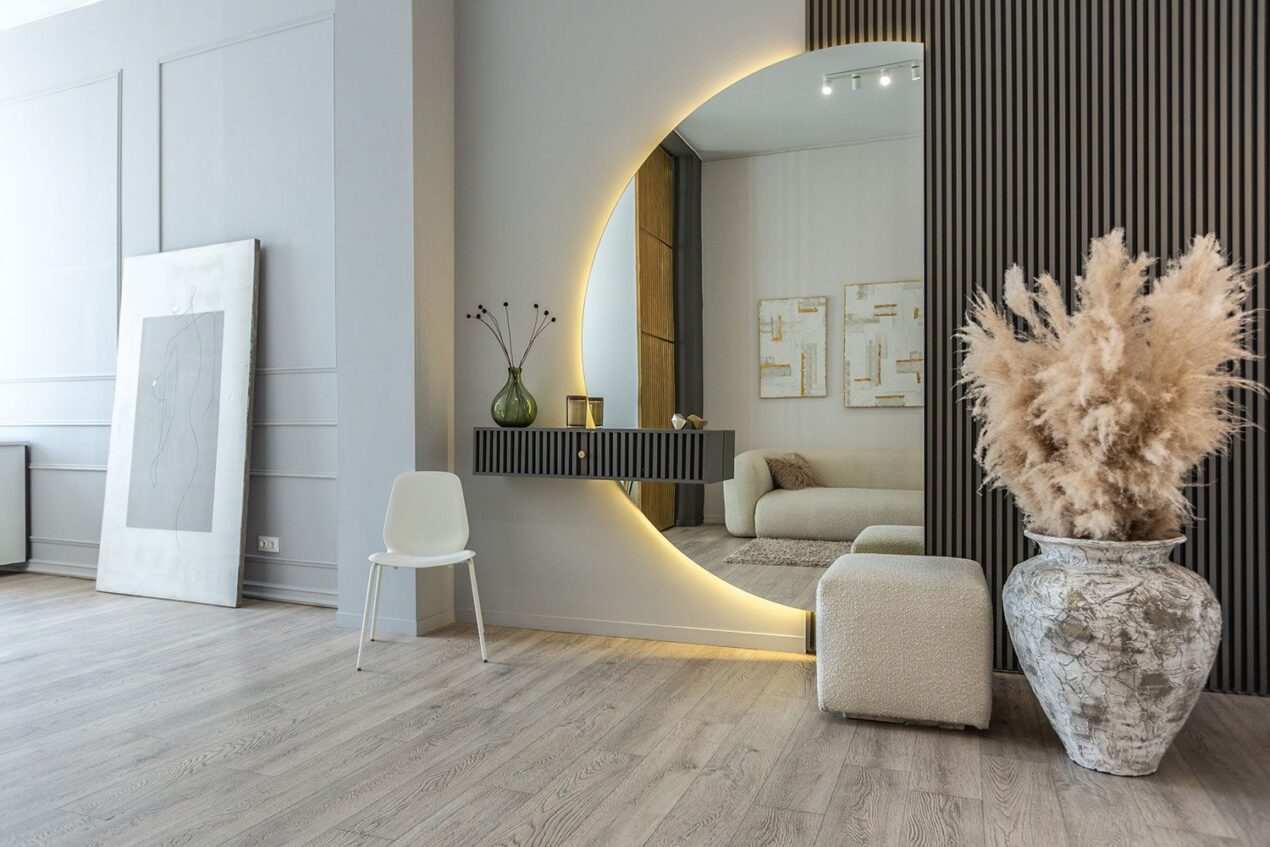 Modern entryway with a large illuminated round mirror and contemporary decor