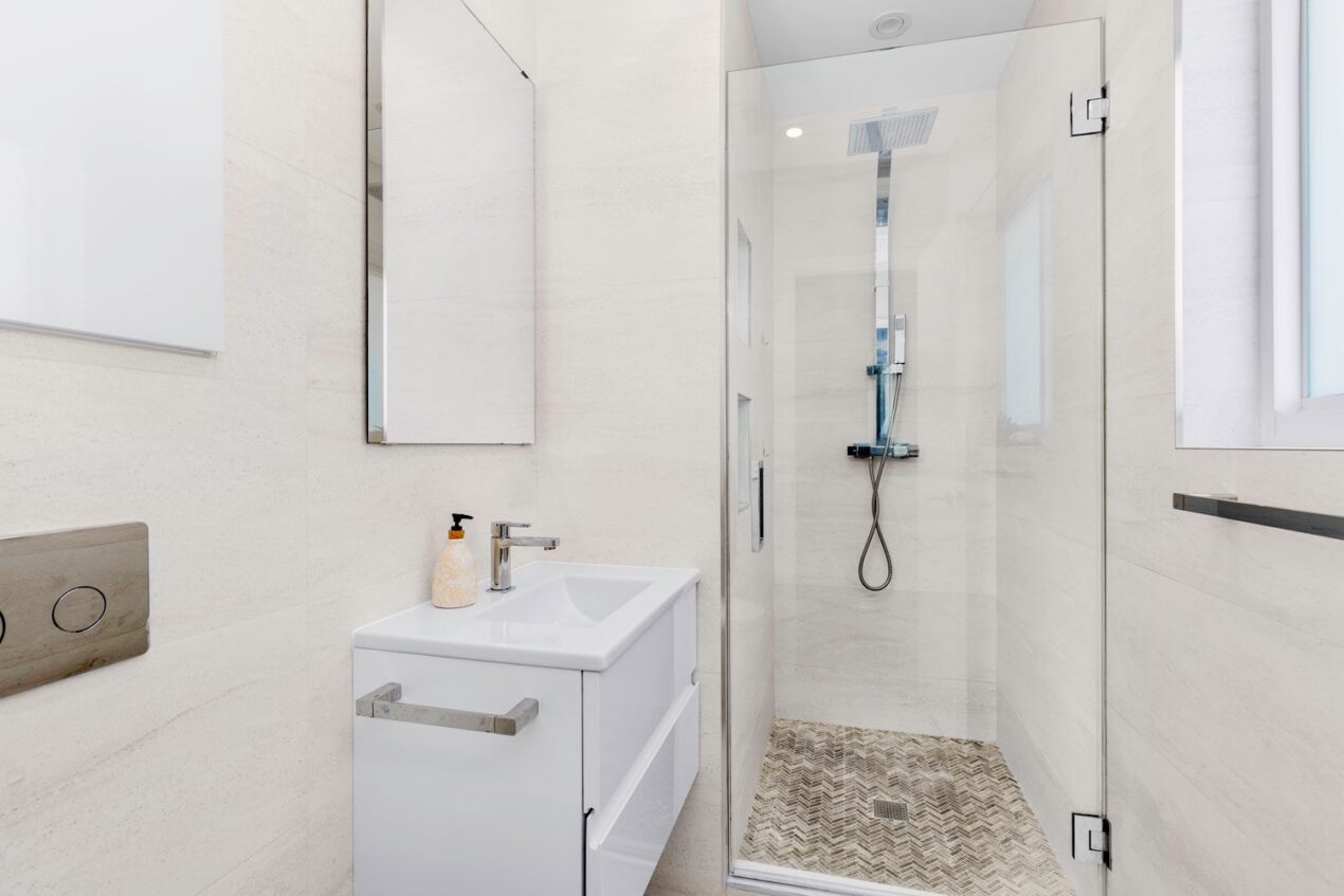 Compact bathroom with frameless glass shower screen doors and a floating white vanity