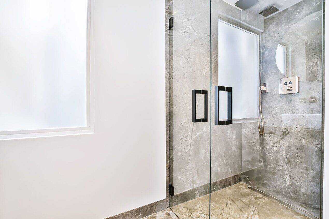 Elegant marble bathroom featuring frameless sliding shower doors and matte black hardware