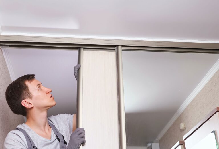 Sliding wardrobe doors and tracks being professionally installed in a modern bedroom