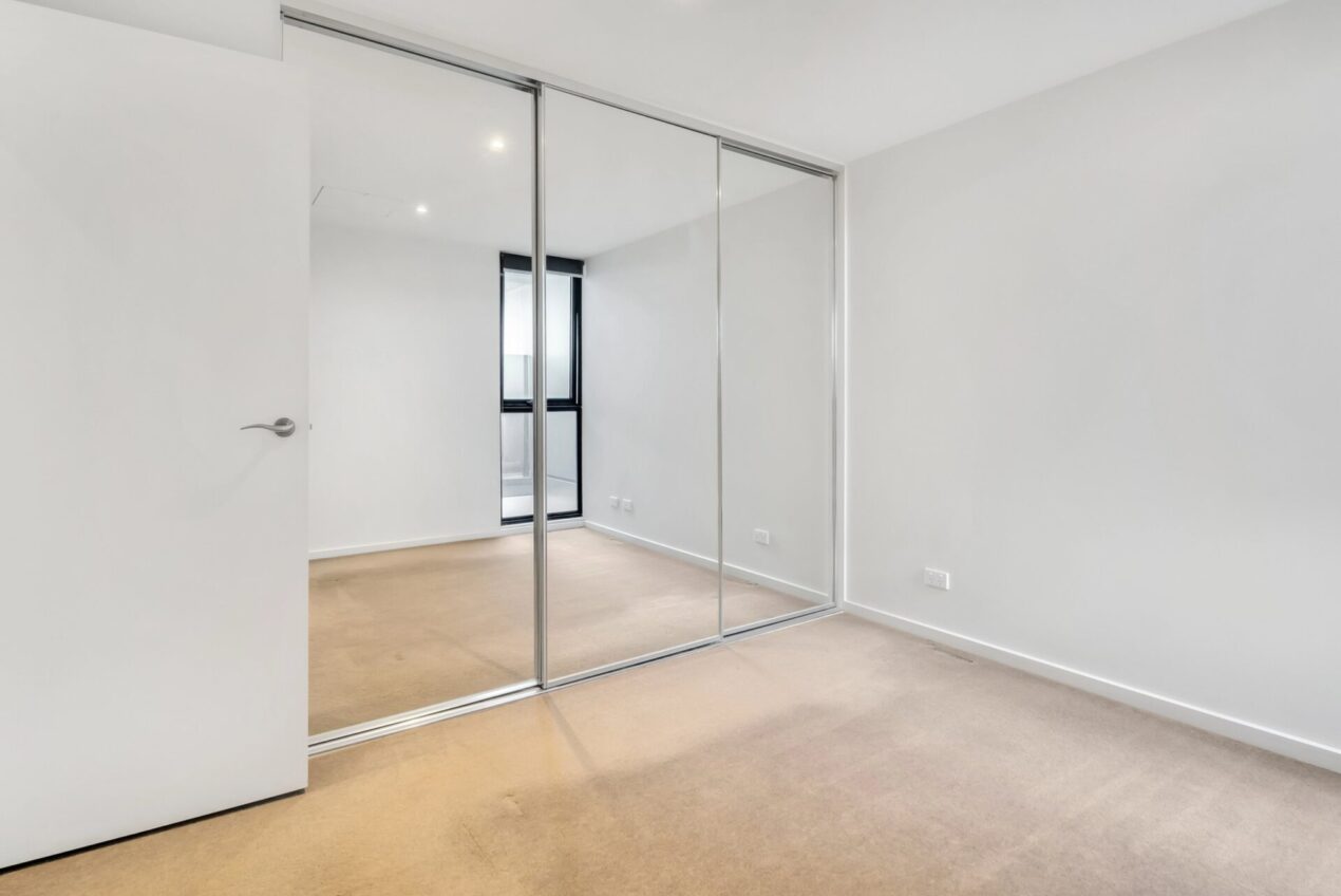 Sliding mirrored wardrobe doors reflecting an empty bedroom