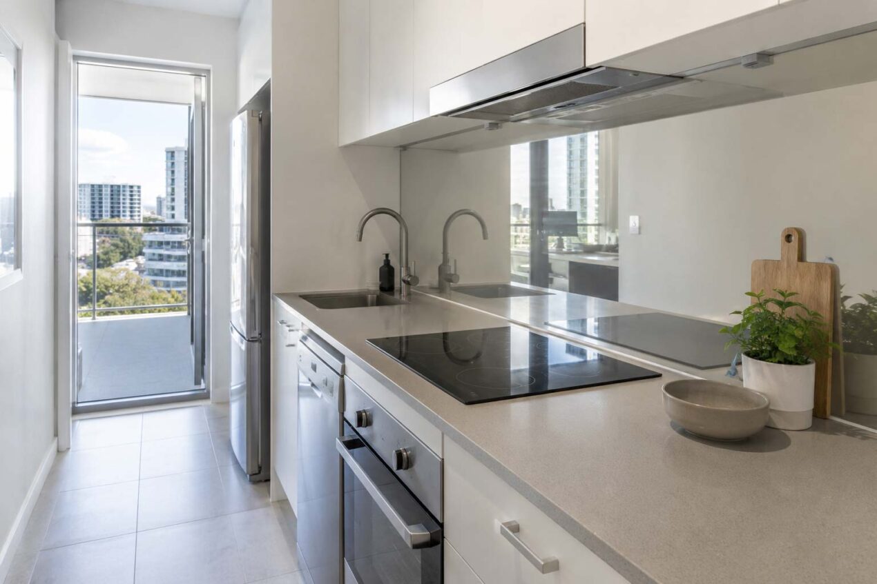 Small Gold Coast kitchen with a reflective glass splashback adding light and depth