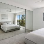 Frameless sliding wardrobe doors in a minimalist Gold Coast bedroom