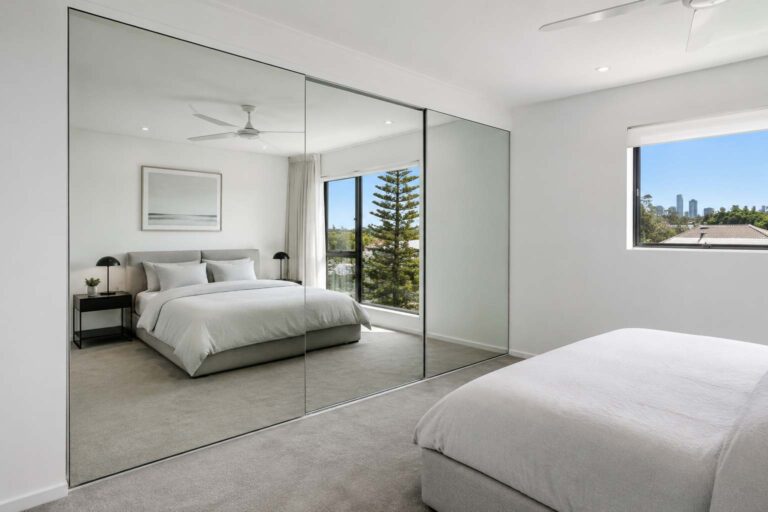 Frameless sliding wardrobe doors in a minimalist Gold Coast bedroom