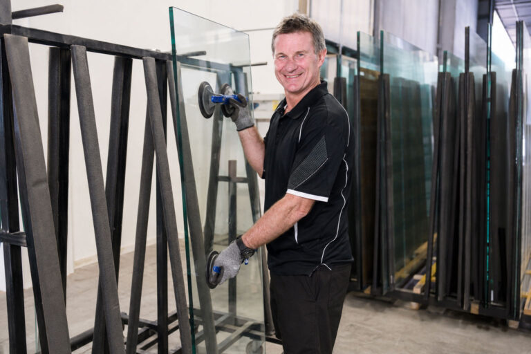 Experienced craftsperson assembling a custom shower screen at the Nerang factory