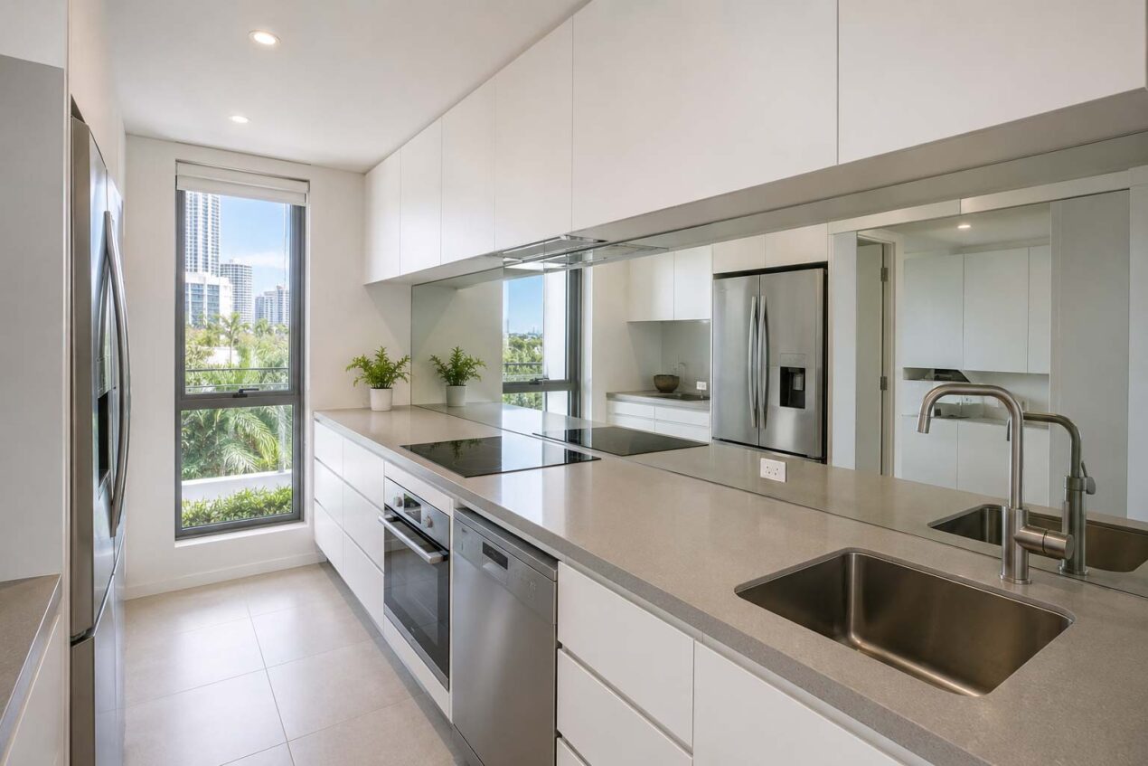 Small Gold Coast kitchen with a mirror splashback reflecting light and space